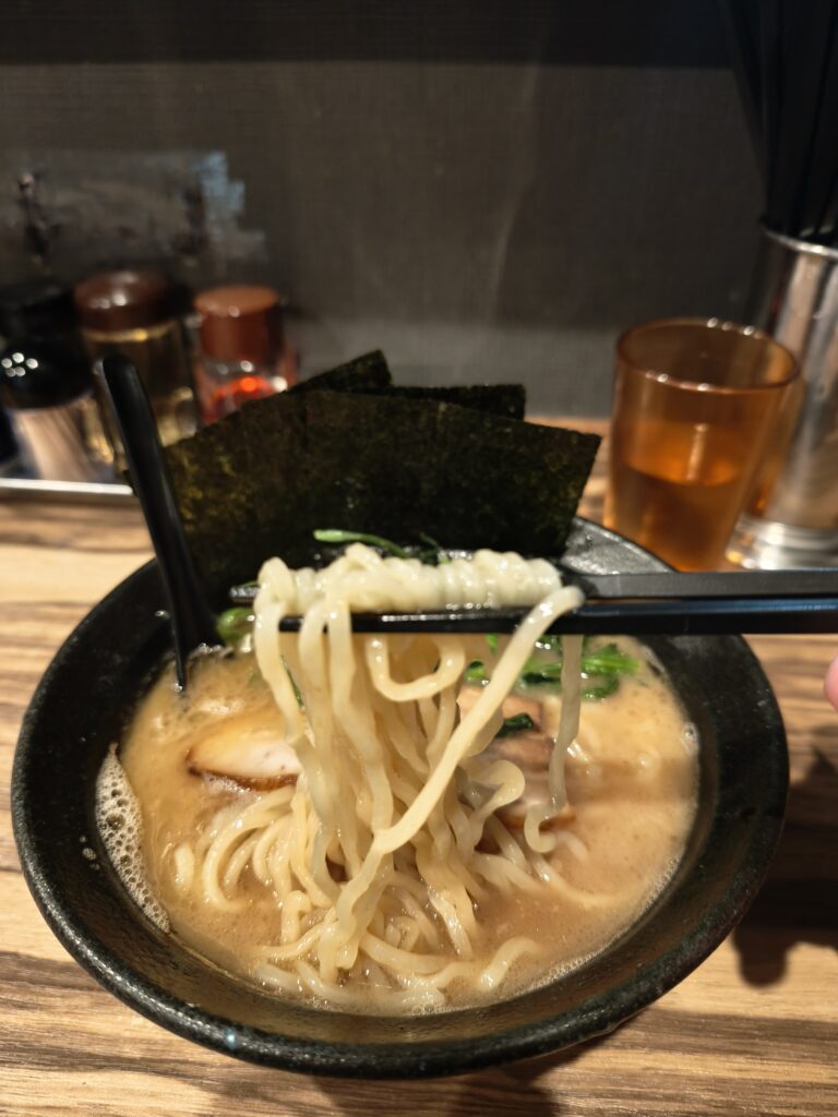 石川家大宮店のラーメン、スープがよく絡んだモチモチの中太麺の麺リフト