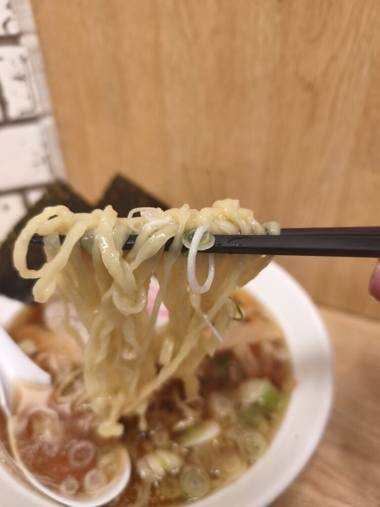 佐野ラーメン特有の平打ちピロピロ麺を箸で持ち上げた様子