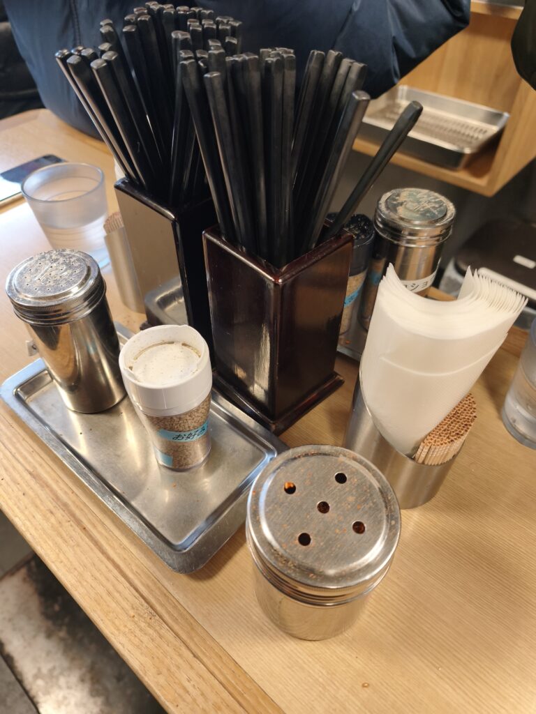 カウンターに並ぶ胡椒や七味などの卓上調味料