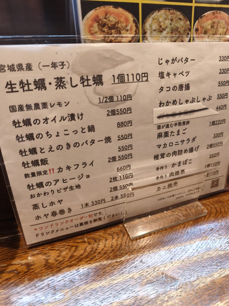 メニュー表。壁に貼られた短冊には「牡蠣1個110円」の文字が目立つ。