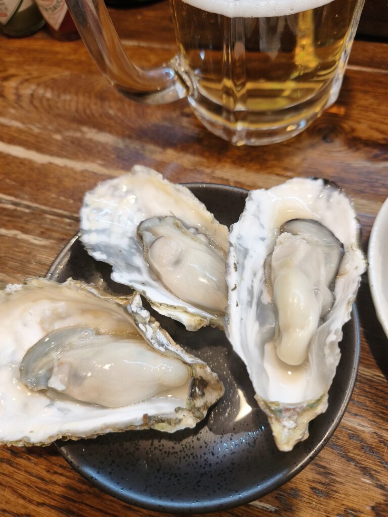 熱々の殻に入った蒸し牡蠣が3つ。湯気が立っており、身はふっくらと縮んでいない。